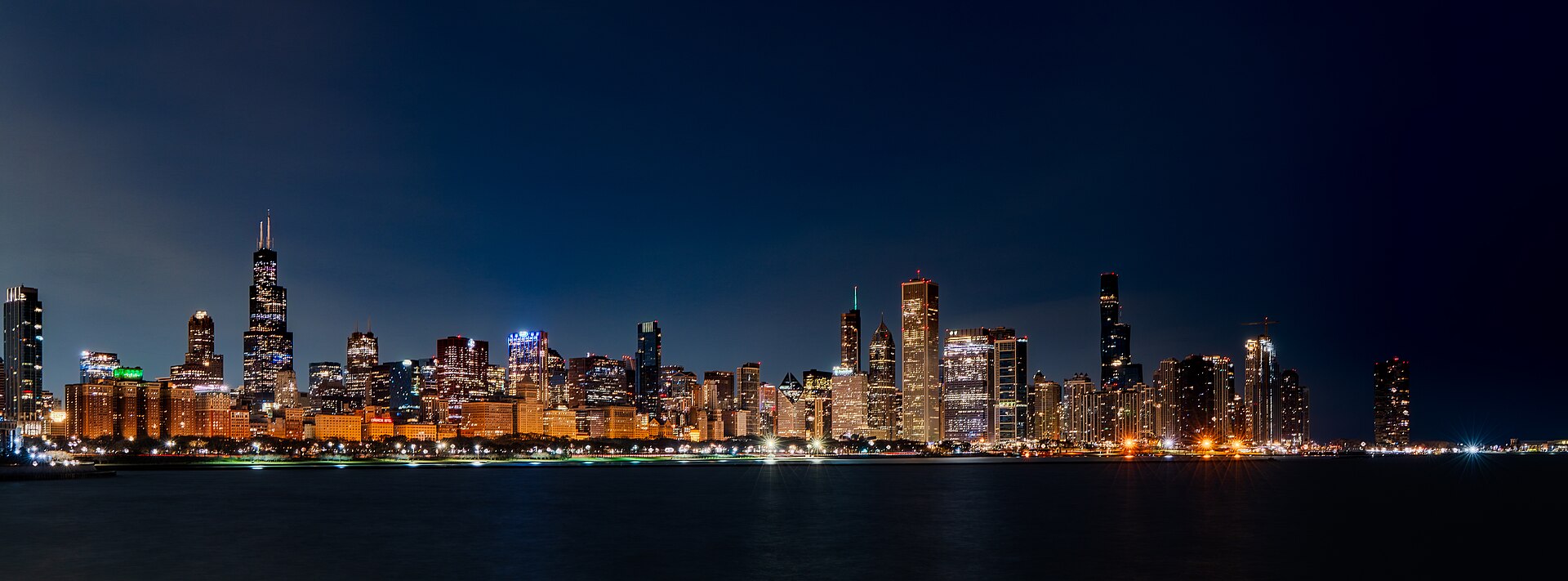 The Chicago skyline across the water before dawn on 15 March 2026, lights still on.